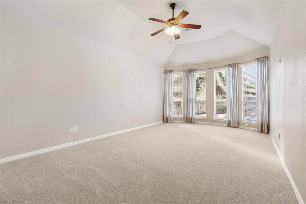 The large primary suite with bay windows overlooking the pool with a ceilling fan and new carpet.