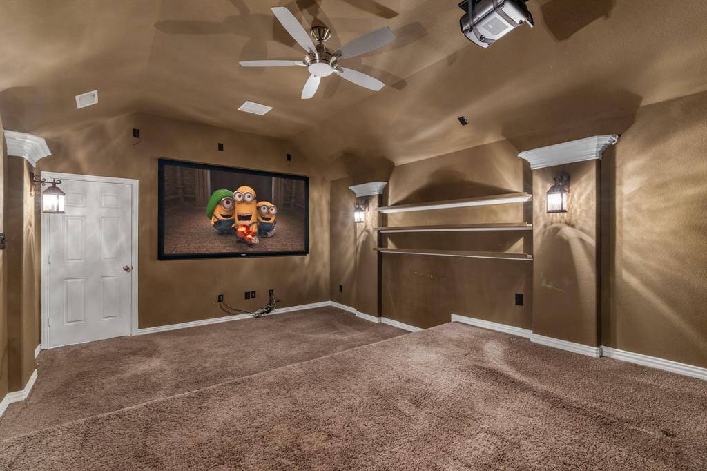 Very large media room with projector and screen, ceiling fan and shelves for DVD's.