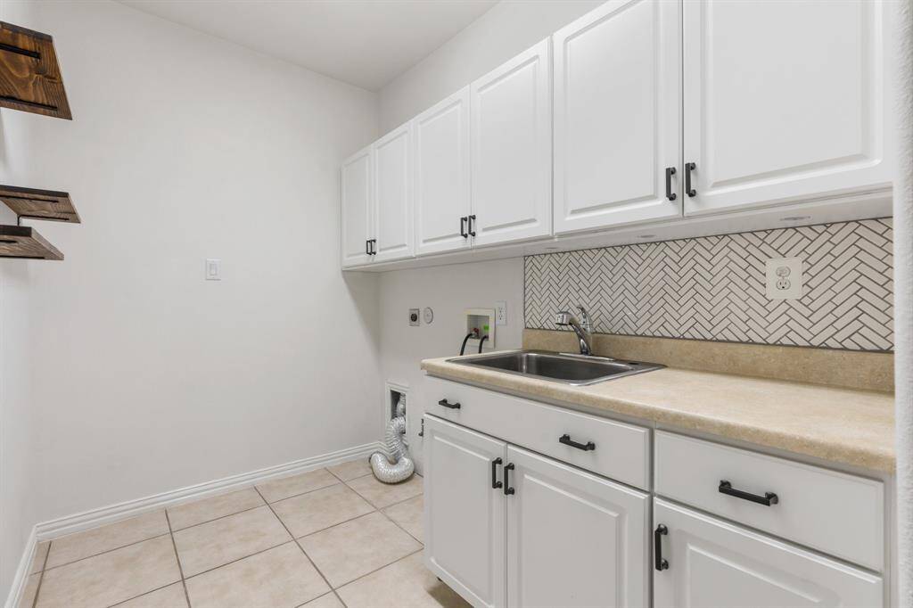 Large updated laundry room with tons of storage and a sink.