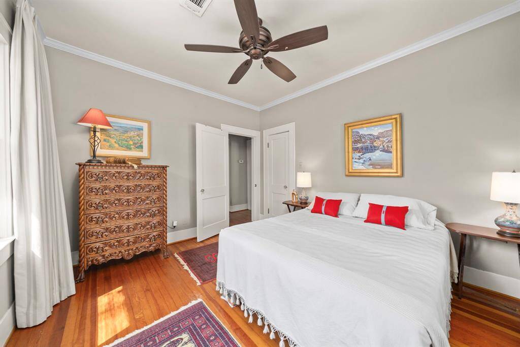 Alternate view of the primary bedroom. Notice the crown moulding, as well as the classic 2 panel doors with vintage hardware and Oak Hardwoods throughout both bedrooms.