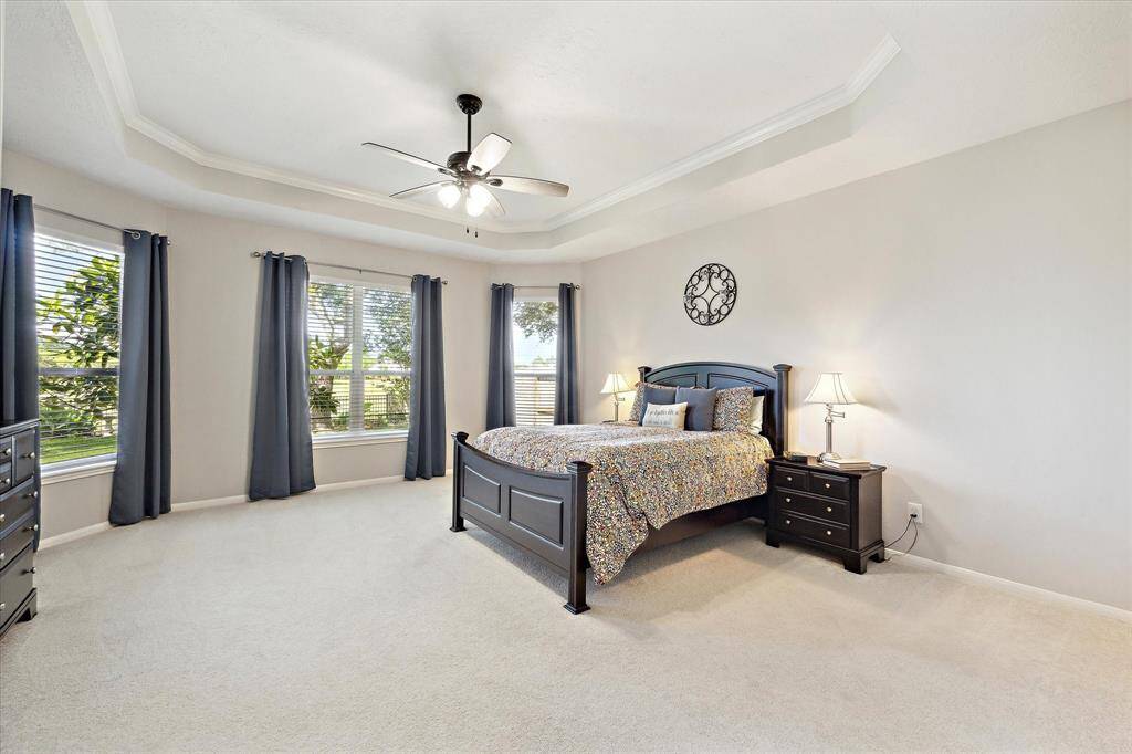 Serenity now! This is your spacious primary retreat with tray ceiling and a view of the lush back yard. There is room for a sitting area as well.