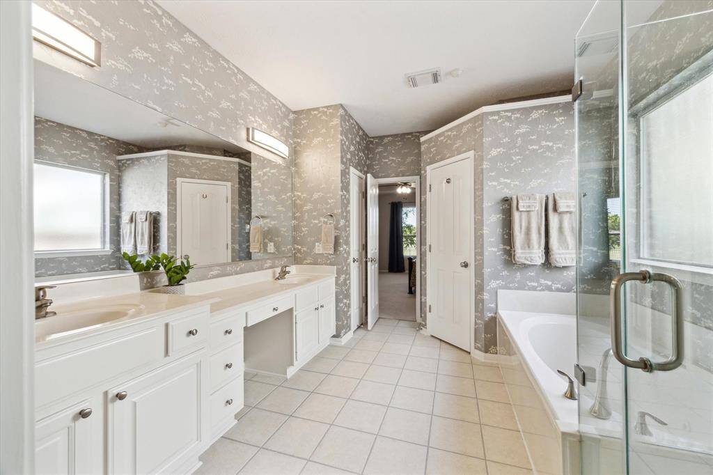 The primary bath in etherial cloud like tones: jetted tub, seamless walk-in shower, double sinks and vanity, water closet, and amazing lighting.
