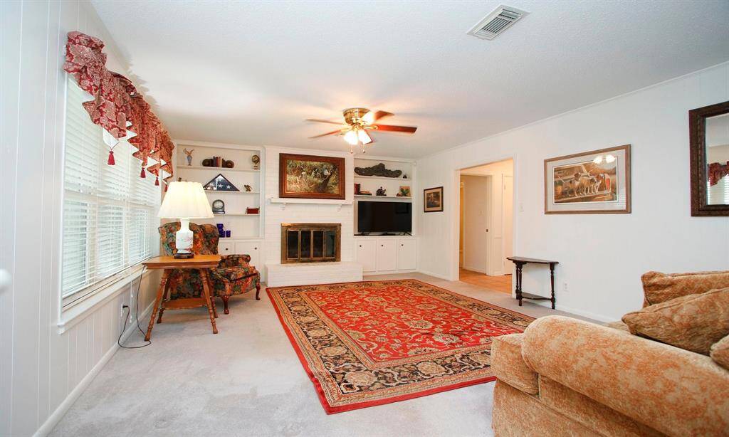 Family Room with view of fireplace and built in shelves and cabinets.   Hallway to the right leads to 3 bedrooms and two baths.