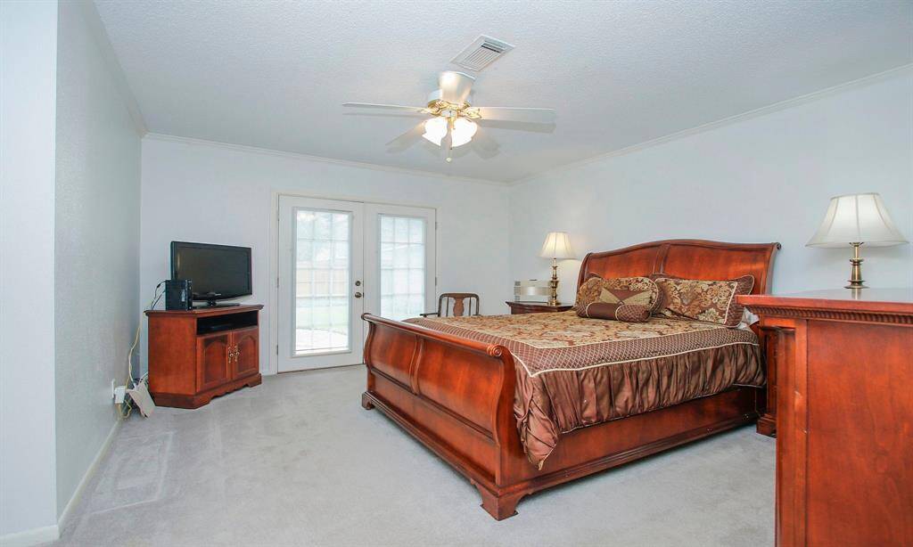 Primary Bedroom with double doors leading to the backyard and pool.
