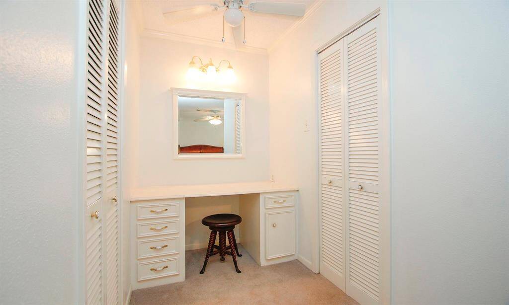 Vanity area in primary bedroom.   Doors on the left open to a walk in closet.  Doors to the right open to the bathroom.