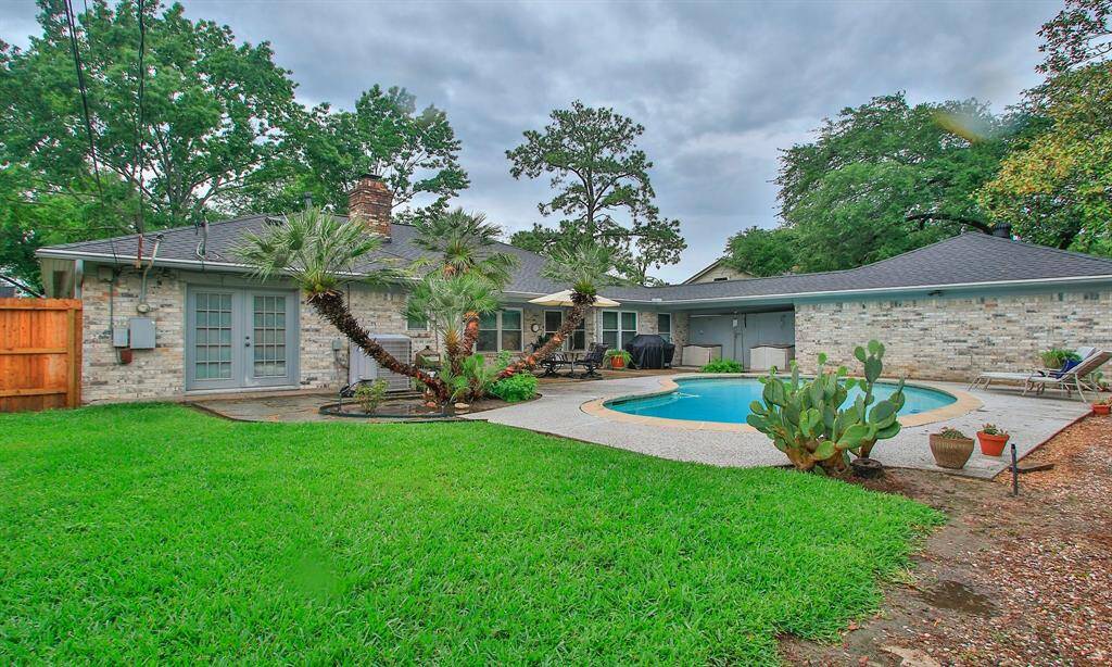Great view of the backyard with green space and pool.