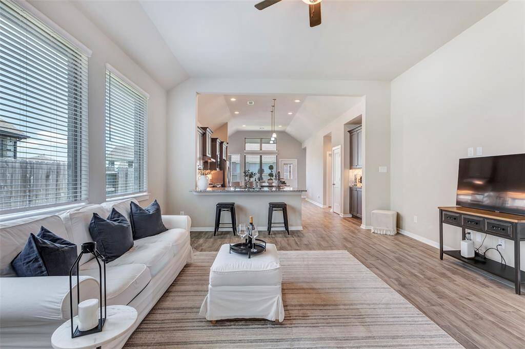 This view of the living room showcases its seamless flow into the kitchen and dining area in the background, creating an open and connected living space.