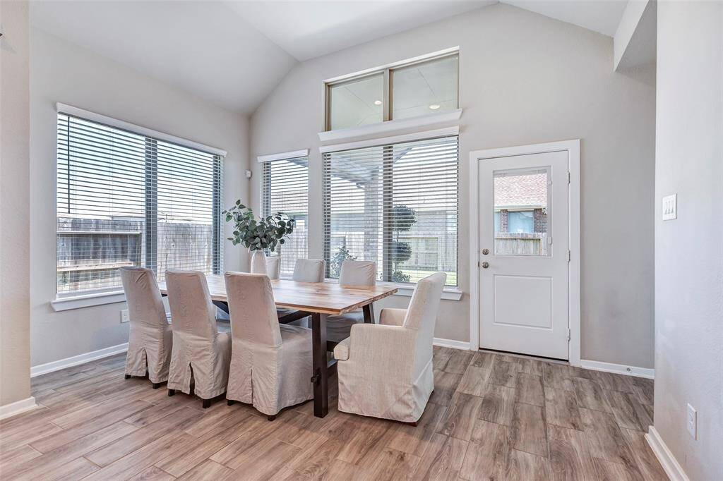Here’s the bright and airy dining area, featuring large windows that offer a lovely view of the backyard. The door provides easy access to the outdoor spaces- the back patio and the backyard.