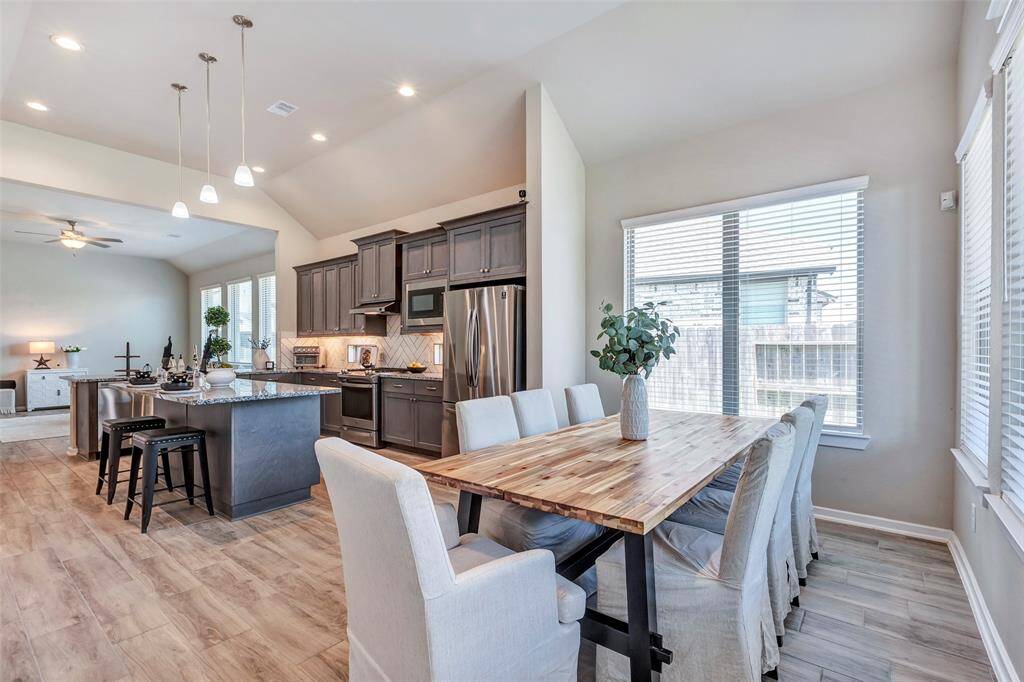 Another view of the dining area, seamlessly connected to the kitchen, with all three spaces—the living room, kitchen, and dining area—boasting coordinated flooring that complements the home's interior colors for a cohesive and inviting look.