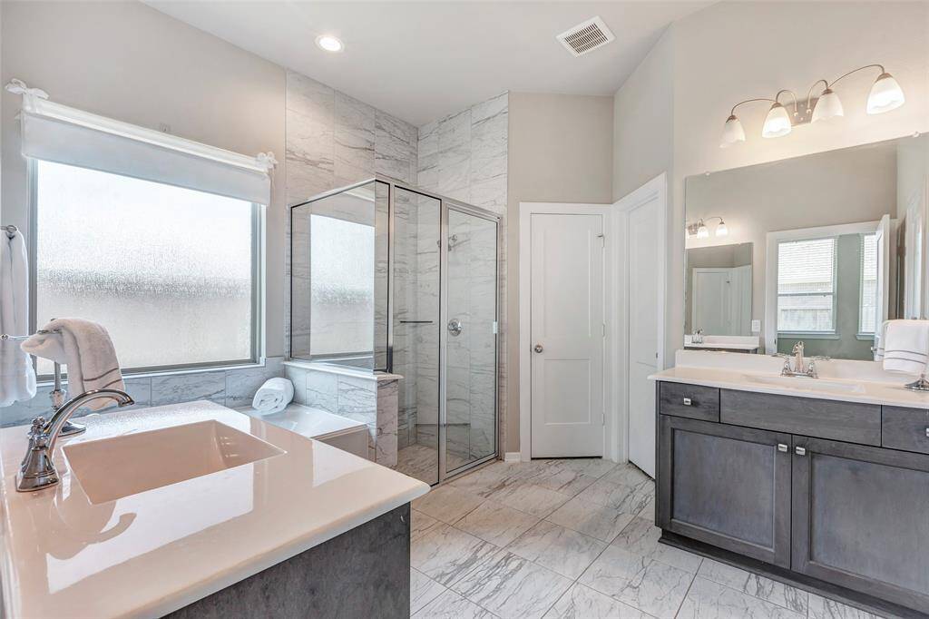 Welcome to the main bathroom, featuring a separate tub and a sleek glass-enclosed shower, offering both relaxation and convenience in a stylish setting.