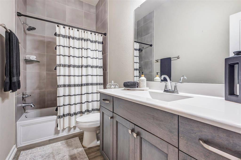 Step inside the secondary bathroom, featuring a convenient tub and shower combo, a large vanity mirror, and ample cabinet space for all your storage needs.