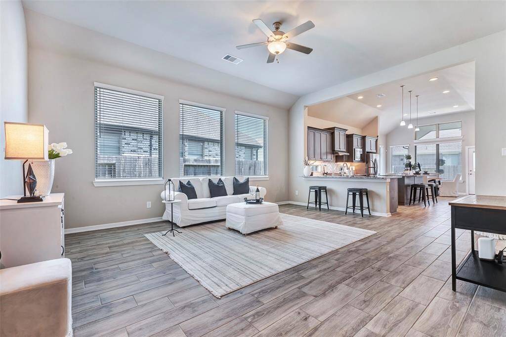 Your first view from the foyer reveals the bright and spacious living room, featuring soaring ceilings and large windows that fill the space with natural light.