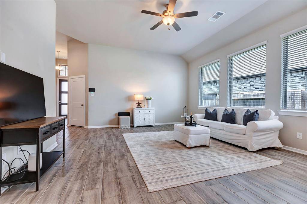 Another angle of the spacious living room, showing a glimpse of the white door that conveniently leads to the attached garage.
