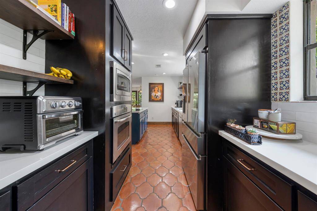 Dark cabinetry and sleek white countertops add contract with ample storage and stainless steel appliances.