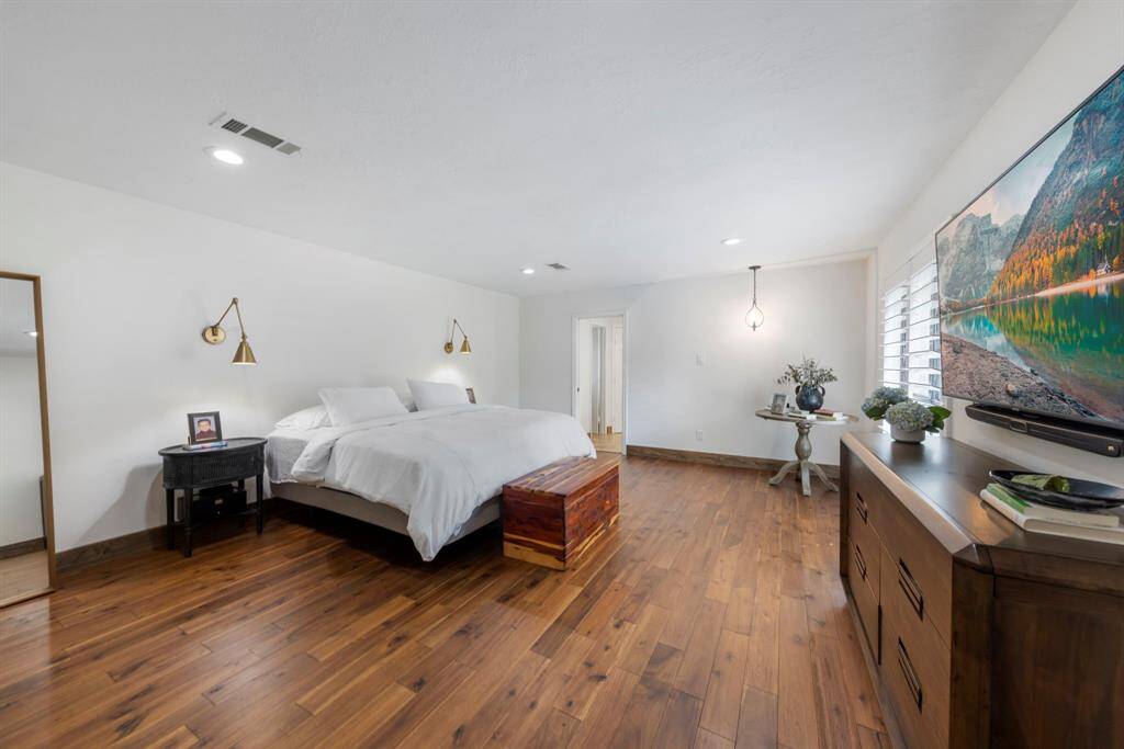 Spacious primary bedroom tucked away towards the back of the home with neutral paint, updated light fixtures, recessed lighting and windows with plantation shutters.