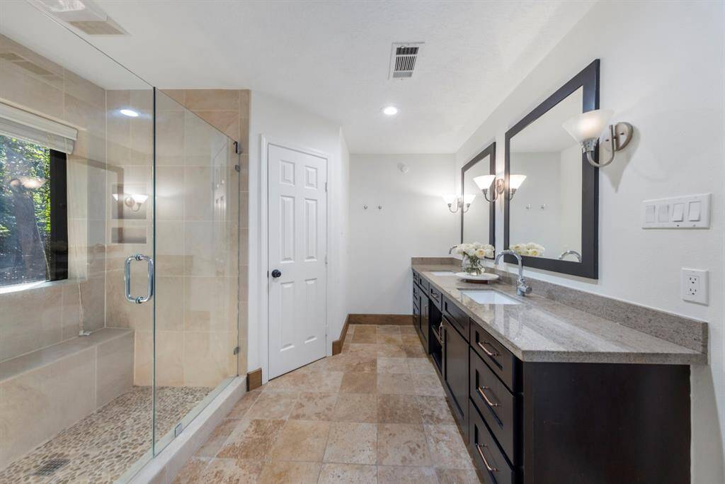 Updated primary bathroom with large, walk-in tile shower and two walk-in closets.