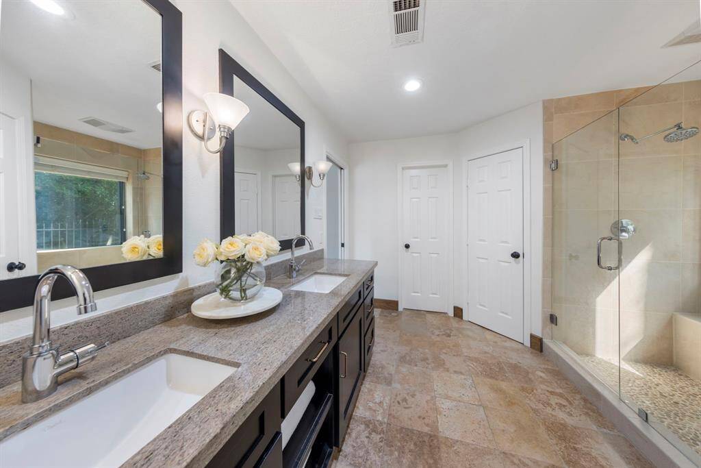 Dual sinks at the vanity with updated faucets and storage beneath.