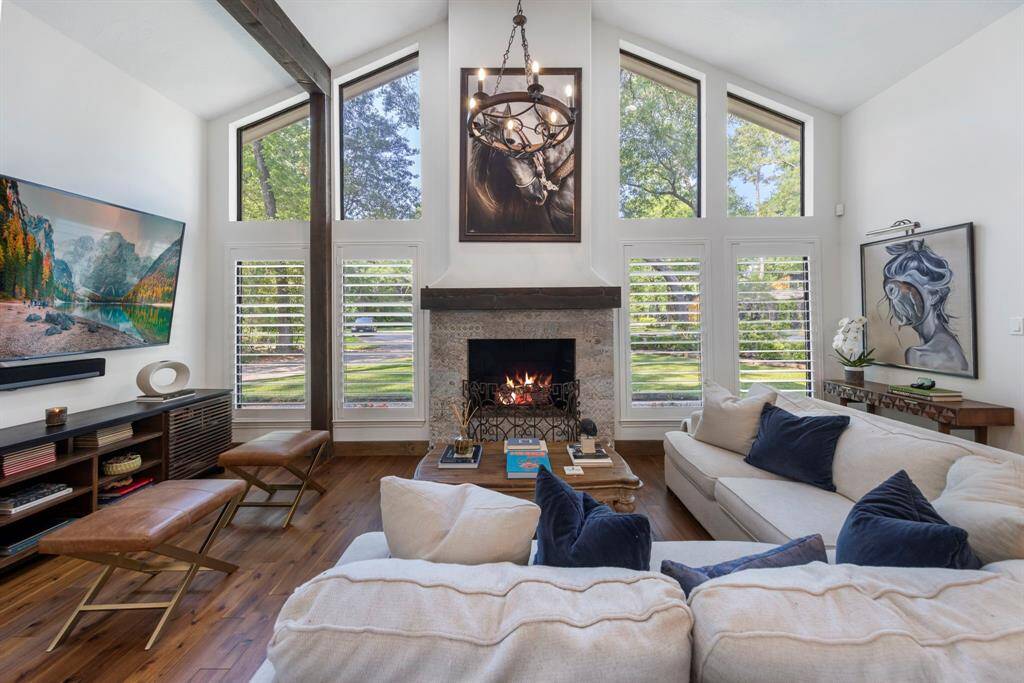The family room feels expansive and airy, thanks to the floor-to-ceiling windows that stretch across one entire wall. Sunlight pours in during the day, casting a warm glow over the rich hardwood floors.