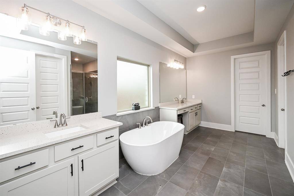 Soothing earth tones fill your huge primary ensuite bath, with dual/separate sinks/vanity, individual wall-wide mirrors, delicate contemporary lighting and delightful, free standing tub.
