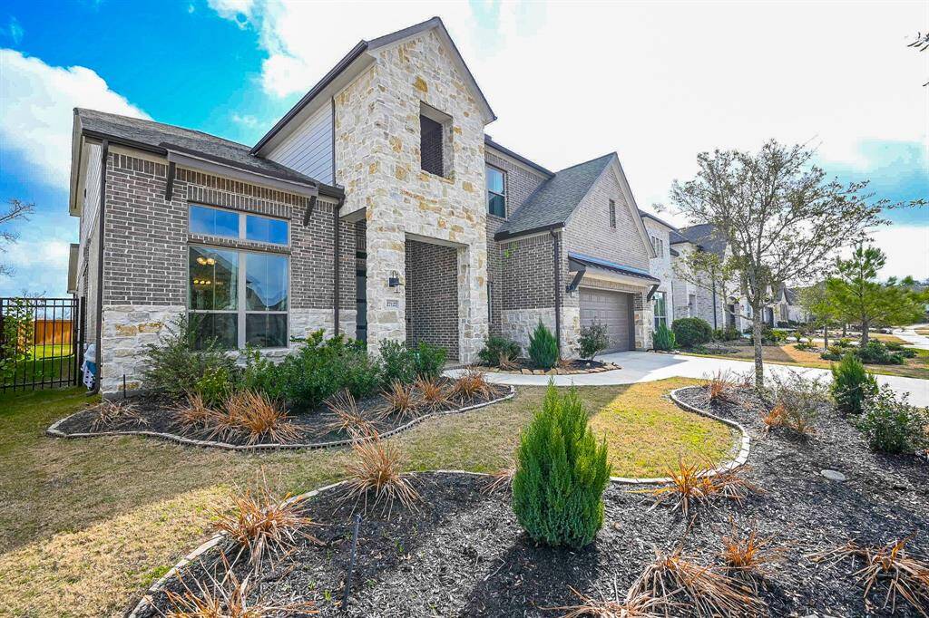 Beautifully maintained, inside and out, this gorgeous residence has NO BACK NEIGHBORS for even more privacy! Shown here, among lush planting beds, are the attached garages, atop a long, pristine driveway, offering both ample parking for family and visitors, with inside storage room, as well.