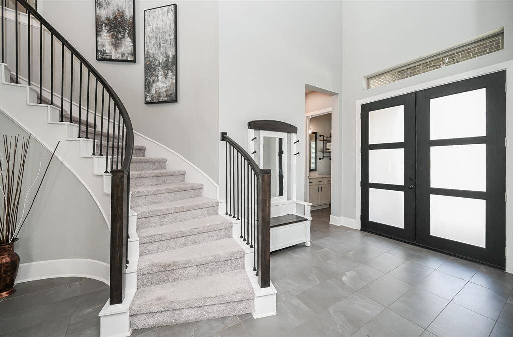 Simple striking dark/light color contrasts bathe the front, contemporary double door entry, as seen from the inside, with the grand, carpeted spiral staircase appearing as a work of art, in itself. Inside, are 5 bedrooms, 4-1/2 baths, all gracing a 9,605 square-foot-lot with 3,639 square-feet of gorgeous interior living space.