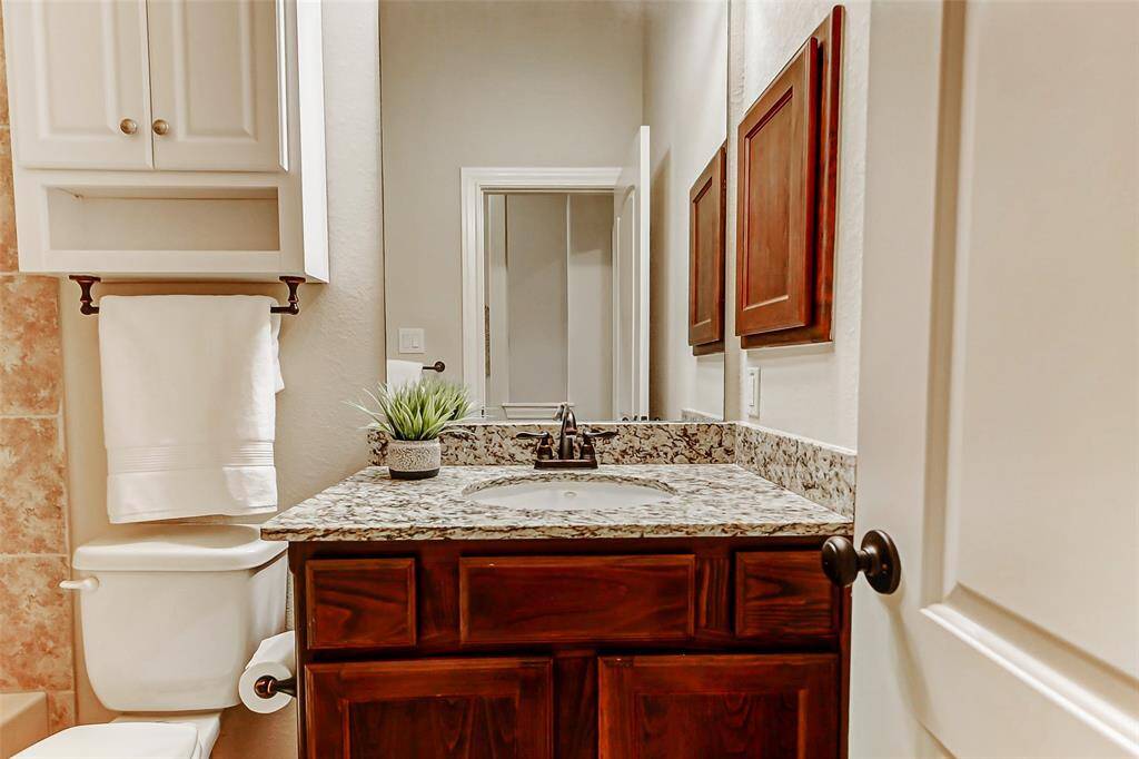 The bathroom features granite counters, rich wood cabinets and a tub-shower combo.