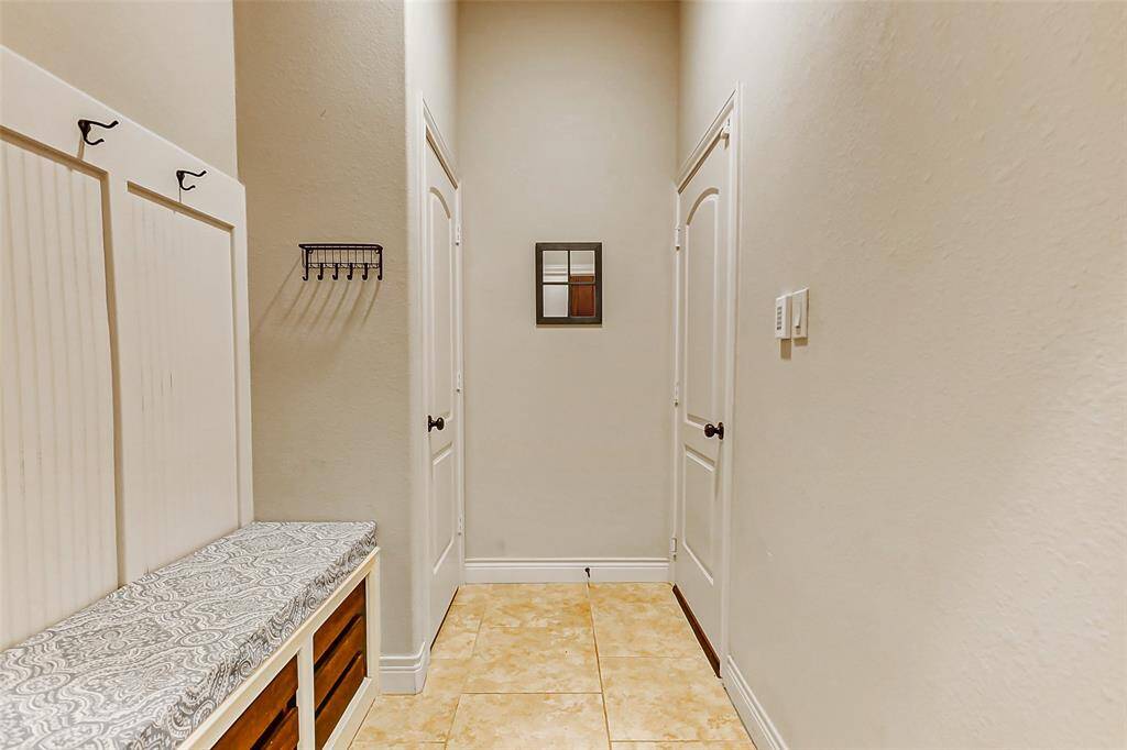 The hallway to the garage features a built-in bench with cushion seating, storage and coat hooks.