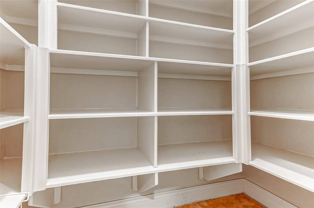 Spacious walk-in pantry with ample shelving for organized storage.