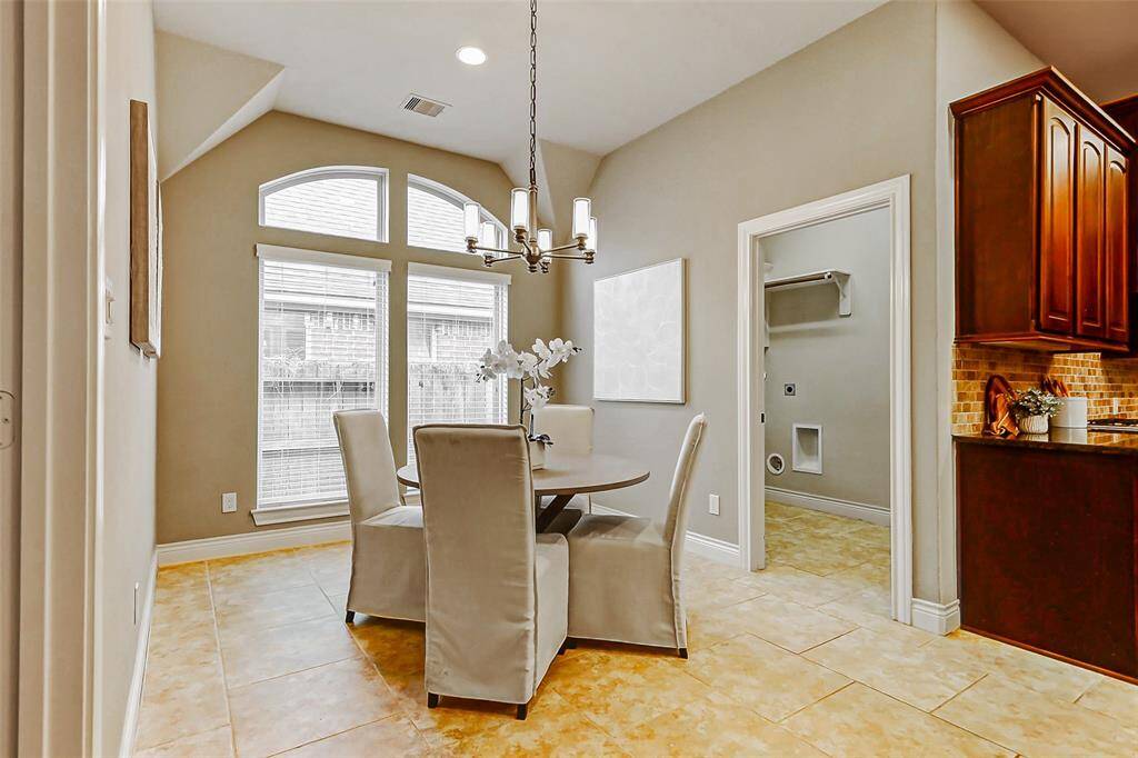 Imagine starting your day in this breakfast area with large windows, high ceiling, and neutral tones. It is adjacent to the utility room and kitchen.