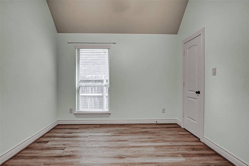 This secondary bedroom is spacious and features wood flooring, ceiling fan and high ceilings.