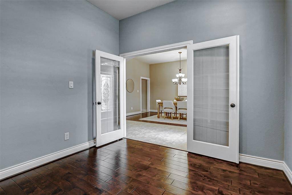The office is located to the left of the front door and features wood floors, high ceilings and French doors.