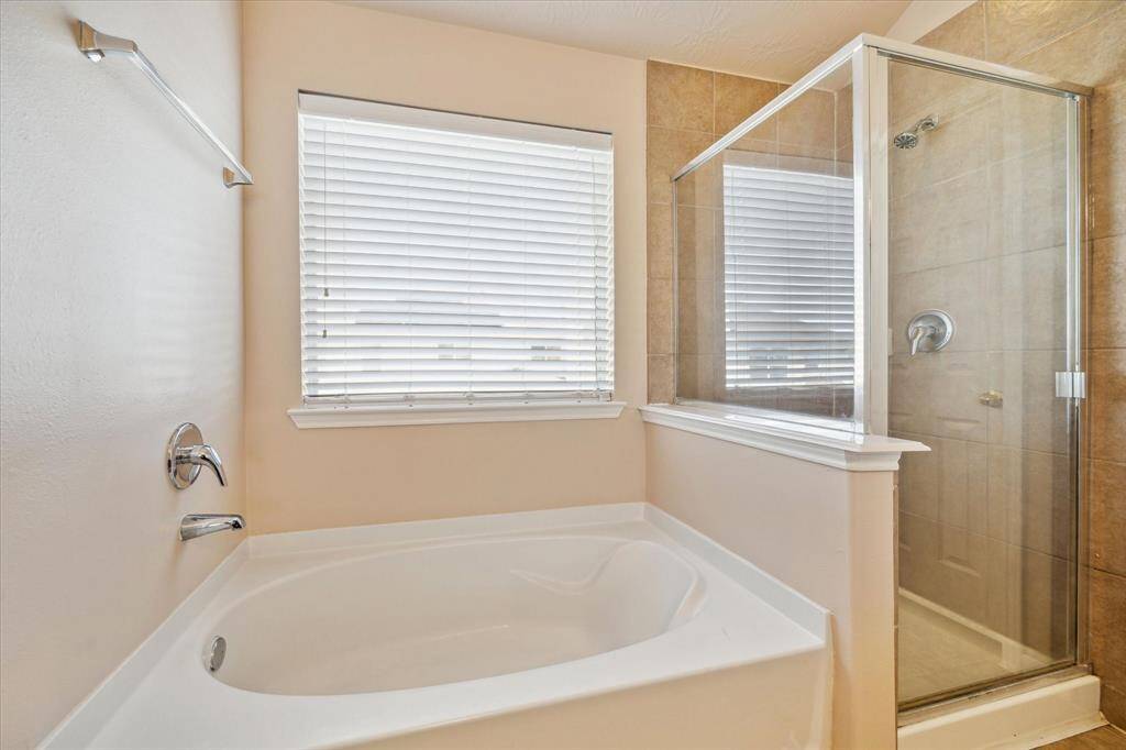 Primary bathroom features a spacious bathtub and a separate glass-enclosed shower