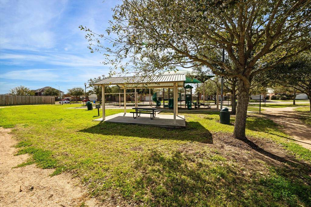 Community park with a covered picnic area, playground equipment, and trees providing shade. It's an inviting place for outdoor activities and family gatherings, enhancing neighborhood appeal.