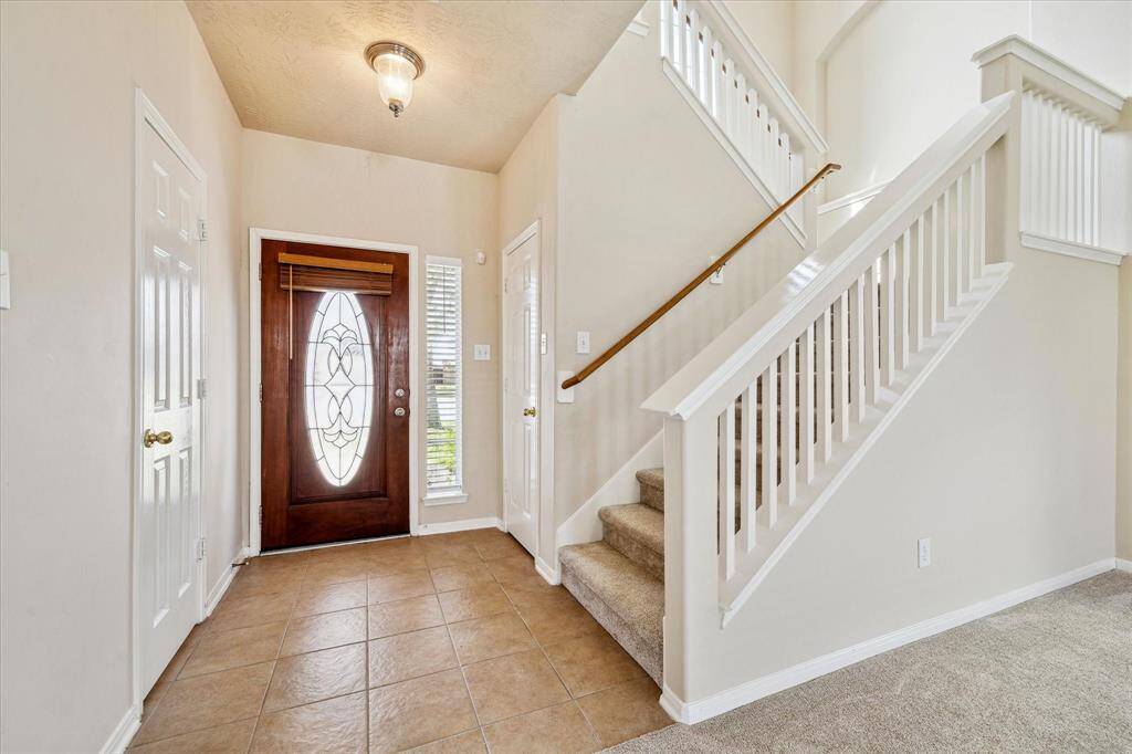 Welcoming entryway with a decorative glass front door and tile flooring