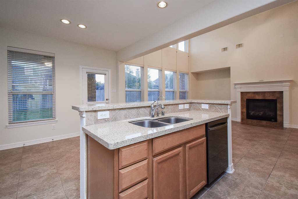 The kitchen island with a double sink, granite countertops, and a built-in dishwasher. The space is very bright from the large windows in the living area!