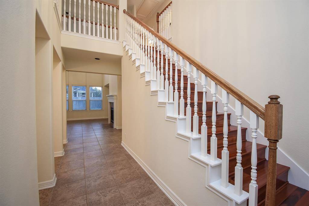 The foyer area is well-lit with its large windows and leads to the family room with a fireplace, creating a welcoming and open atmosphere.