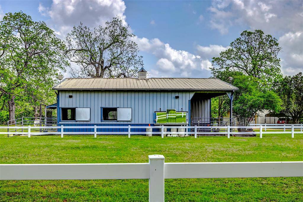 The riding area is lit and enclosed by a white vinyl fence.