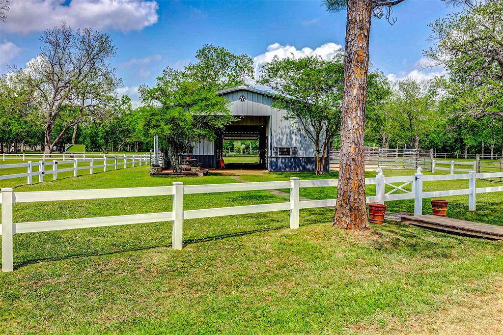 Horse barn with lit riding arena and cross fencing with non-climb horse fencing and electric tape. Interior fencing is white vinyl fencing.