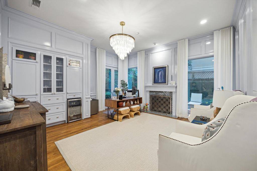 First floor study located between the Powder room and kitchen is painted with European paint of Europe.  The paint is a high gloss enamel and is truly a work of art.  Separate wine refrigerator and ice maker as well as custom lighted built-ins flank the side wall.  Custom draperies to remain.  Fireplace surround is a custom glass tile that really offests this room.  Ease of access to grounds through French door behind office seat.