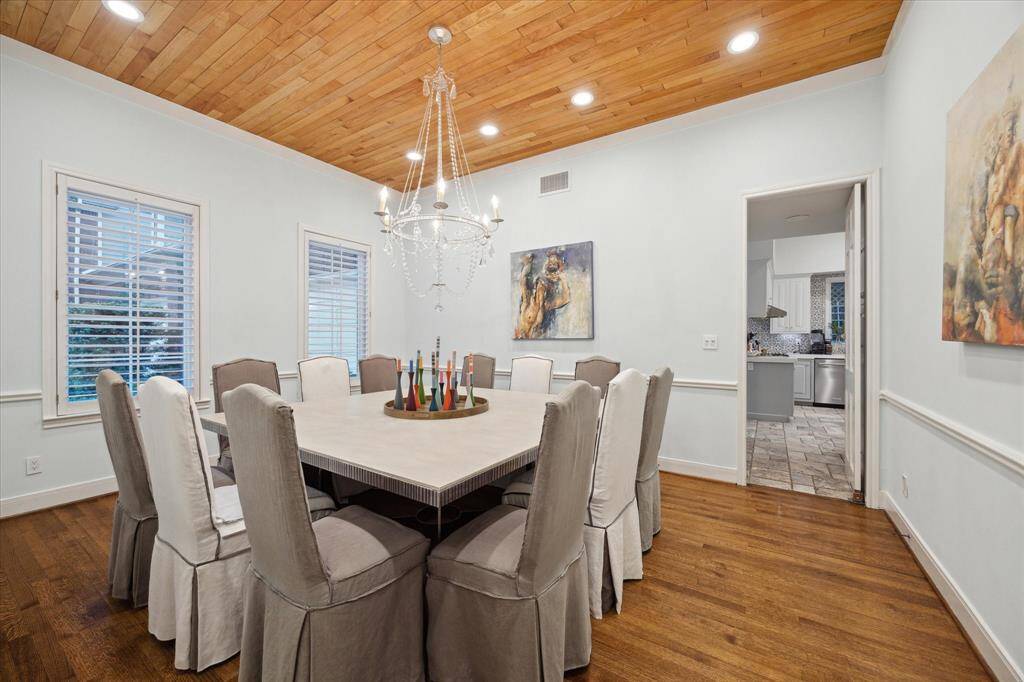 Formal Dining has great lighting coming in from the front courtyard.  Plantation shutters can direct the amount of light illuminating the room.  Custom solid wood plank ceiling with chandelier by J. Randall Powers.  All wood floors are laid on screed and so are true wood that can be refinished. Swinging door leads to/from kitchen.