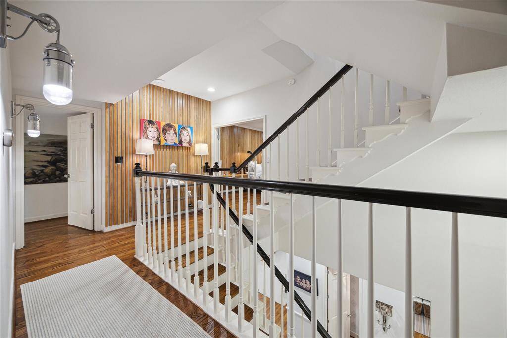 Second floor landing with custom White Oak wall, lighting fixtures and ample light traveling through the step cavity.