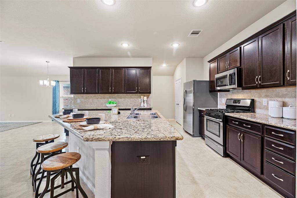 The sprawling island with breakfast bar seating serves as a versatile centerpiece, providing additional workspace, storage, and seating for casual dining or entertaining.