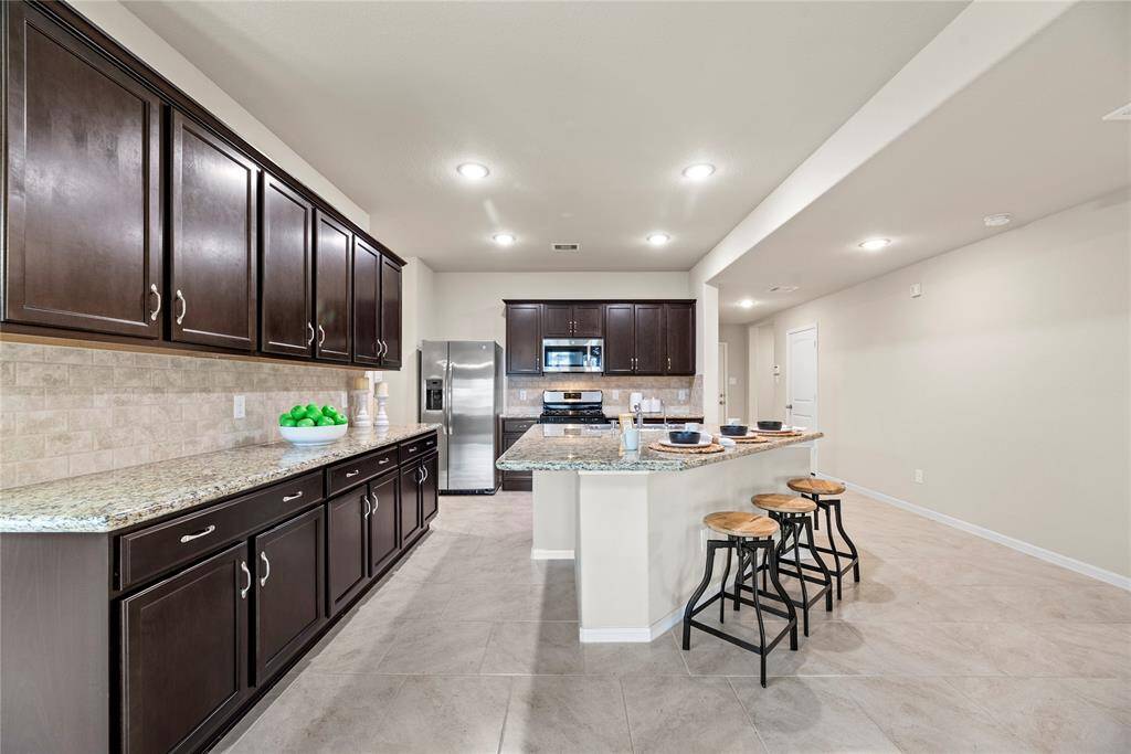 Granite countertops paired with a coordinating stone backsplash not only provide a durable and elegant surface for food preparation but also add a touch of luxury and sophistication to the kitchen.