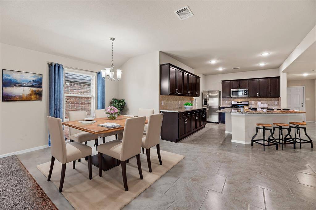 The dining area is ideal for a full-sized table and features beautiful tiled floors, a large bright window, and overhead chandelier.