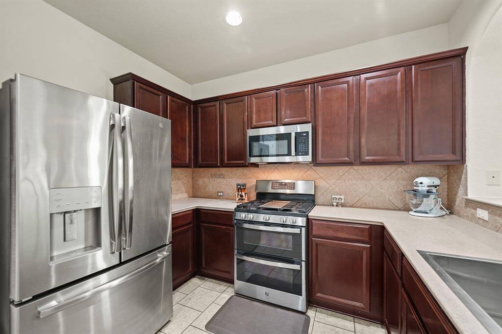 The stainless steel appliance package includes a 4-burner gas range with double conventional ovens below, microwave oven with ventilation & lighting above and a dishwasher. The microwave oven and dishwasher were replaced in 2024 and as an added bonus, the stainless steel French door refrigerator with door mounted ice/water dispenser and full size washer & dryer will remain with the home!