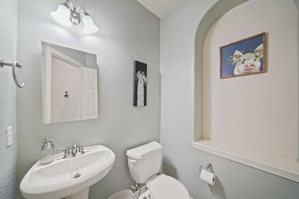 Convenient for guests, the first floor half bath features a pedestal sink with a wall mounted beveled mirror/medicine cabinet, wall mounted lighting, arched & recessed art niche & tile flooring.