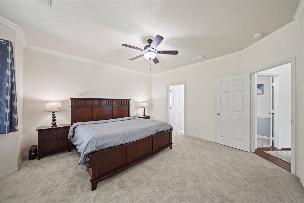 A view of the owner's bedroom with access to a private bath shown in the background.