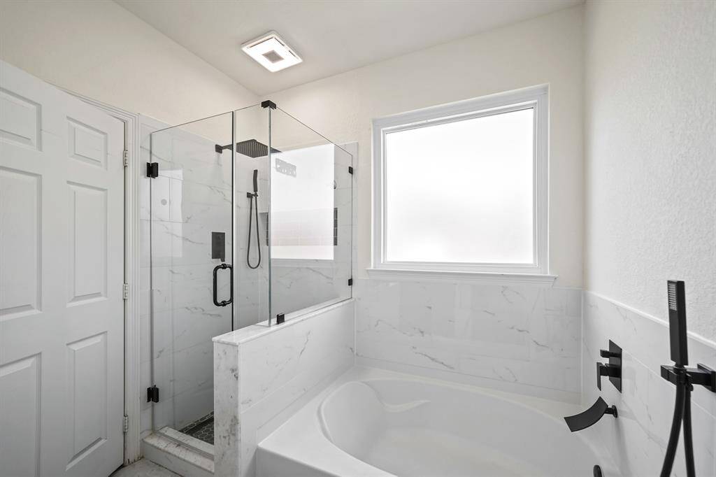 Relax and unwind in the tile surrounded soaking tub complete with wall mounted plumbing fixtures including a hand held shower wand and private glass window above. Sitting just next to the tub is a walk-in tile surrounded and frameless glass enclosed shower.