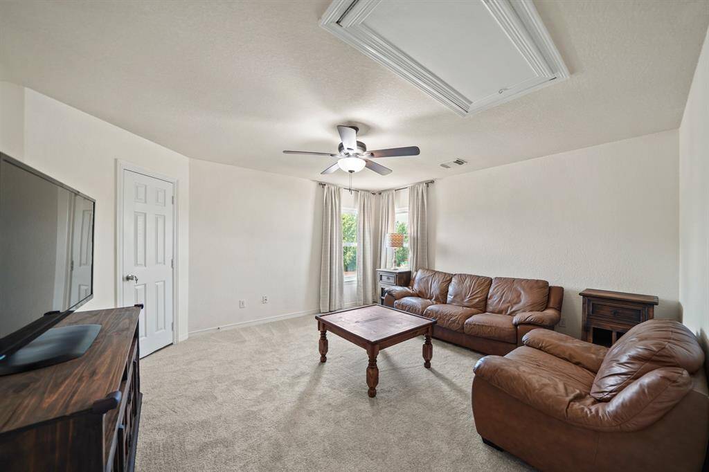The seond floor game room has a ceiling fan with light fixture, access to a floored attic storage area and carpet.