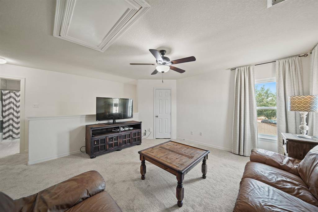 A large window with drapes overlooks the backyard and fills this space with natural light.